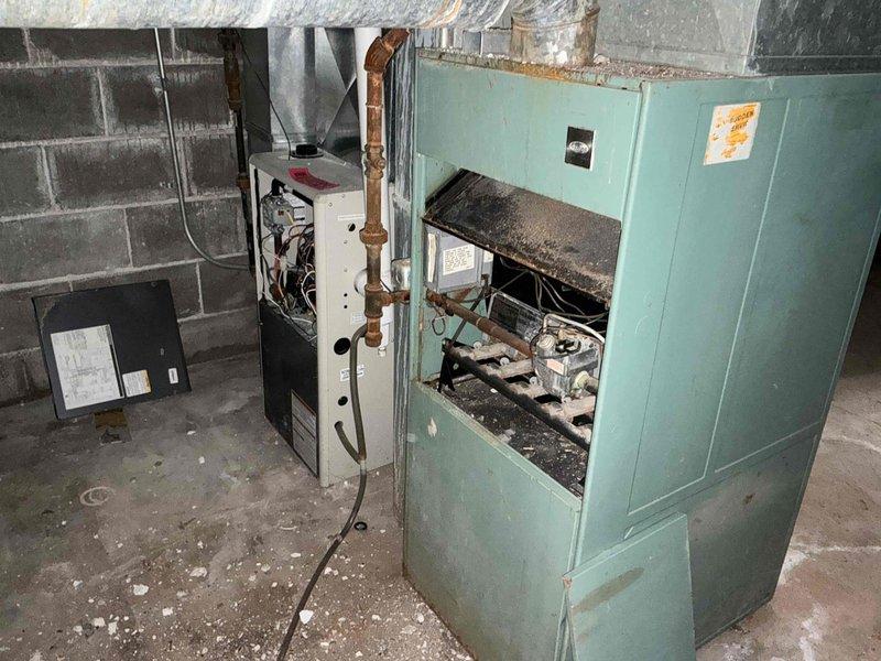 Completed comprehensive assessment of aging HVAC system in commercial mechanical space for equipment replacement estimate. Evaluated existing turquoise cabinet-style furnace showing significant deterioration, faded exterior finish, exposed internal components, and accumulated dust buildup indicating end of serviceable life. Documented large metal ductwork, insulated flexible ducts, and associated piping infrastructure throughout mechanical room, noting surface corrosion on overhead pipes and overall system condition. Provided detailed photographic documentation and replacement recommendations for outdated heating and air distribution equipment to improve efficiency and reliability.