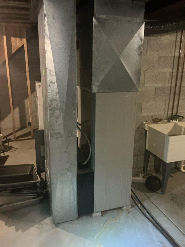 Conducted comprehensive assessment of existing HVAC system in basement utility area for complete replacement estimate. Evaluated current furnace unit with exposed internal components, including gas valve assembly, electrical connections, and mechanical systems, documenting equipment condition and accessibility for future installation. Photographed existing ductwork configuration, including vertical metal chase running floor to ceiling, and assessed surrounding workspace conditions to determine material requirements and installation logistics for proposed system replacement.
