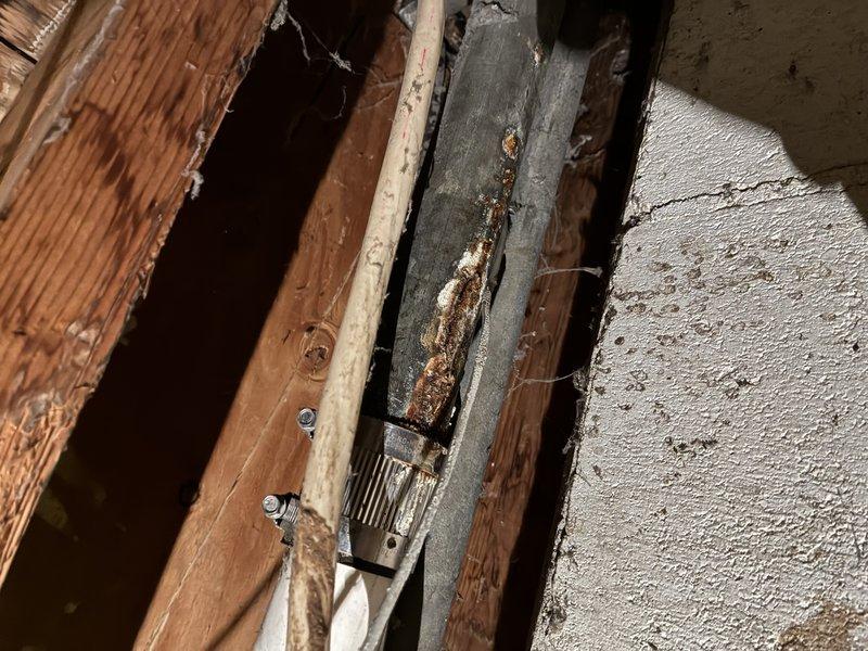 Responded to emergency call for burst pipe in interior wall cavity. Upon inspection, discovered compromised 1-1/2" PVC Schedule 40 drain line with failed connections and significant water damage to surrounding structural components. Removed damaged sections of pipe and corroded metal reinforcement brackets that had deteriorated due to prolonged moisture exposure. Installed new PVC piping with proper rubber coupling clamps to ensure secure, leak-free connections between pipe sections. Verified all joints were properly seated and tightened to manufacturer specifications. Tested repaired line for leaks and confirmed proper drainage flow. Addressed water damage concerns and documented condition of surrounding wooden framing members for potential follow-up structural assessment.