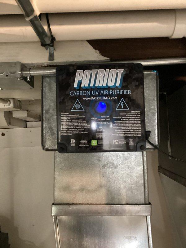 Completed installation of new HVAC system including furnace with integrated air purification. Installed PATRIOT Carbon UV Air Purifier unit within the ductwork system to provide enhanced indoor air quality through ultraviolet light technology. Routed and secured white PVC condensate drain line through exterior foundation wall with proper mounting brackets and elbow fittings, terminating at ground level with appropriate drainage to landscaped area. All ductwork connections sealed and secured to manufacturer specifications, electrical connections completed, and system tested for proper operation and airflow.