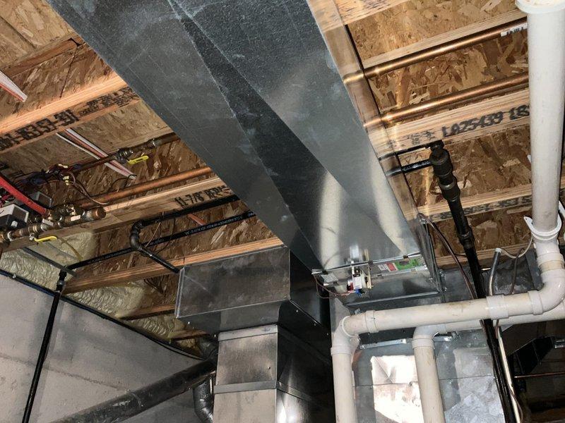 Completed comprehensive HVAC system assessment in unfinished basement utility space to provide equipment replacement estimate. Documented existing mechanical infrastructure including ductwork, copper refrigerant lines, PEX plumbing, electrical conduits, and ventilation systems routed through exposed ceiling joists. Evaluated current system configuration and accessibility for future equipment replacement installation.