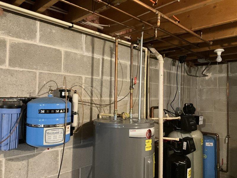 Completed comprehensive HVAC system assessment in residential basement utility area to provide replacement estimate. Evaluated existing dark green air handler/furnace unit with associated metallic ductwork configuration, including curved elbow sections routing along concrete block walls. Documented current system layout, ductwork condition, electrical connections, and mounting hardware to determine replacement specifications and installation requirements for updated heating and cooling equipment.