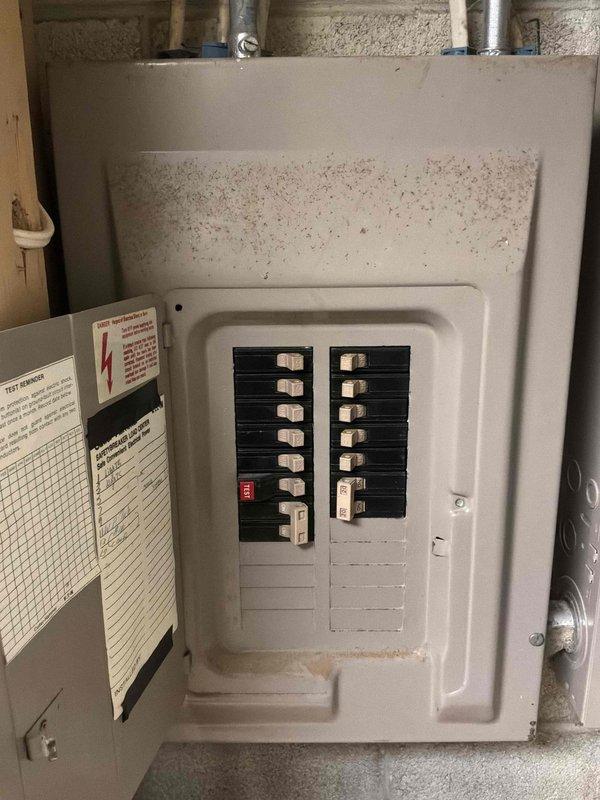 Completed comprehensive assessment of existing HVAC system for replacement estimate. Documented current outdoor condensing unit showing normal wear with debris accumulation on top cover and standard electrical disconnect configuration with PVC conduit routing from exterior wall. Inspected and photographed interior electrical panel in basement utility area, noting existing breaker configuration with one tripped breaker indicator and verifying available electrical capacity for new equipment installation.