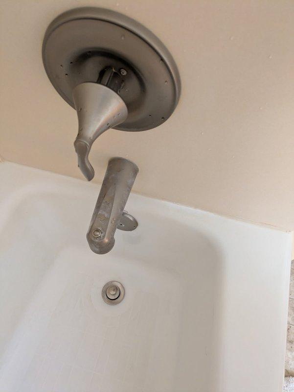 Responded to service call for malfunctioning bathtub diverter and tub spout assembly. Upon inspection, found the diverter handle detached and hanging improperly from mounting position, preventing proper operation of the shower/tub fixture. Removed the existing chrome diverter component and spout assembly from the ceiling-mounted configuration. Secured the diverter mechanism back into proper mounting position, ensuring flush installation against the wall surface. Tested the tub spout and diverter functionality to verify proper water flow direction between tub spout and showerhead. Additionally inspected the bathroom sink faucet and noted mineral deposits on the brushed metal finish but confirmed proper operational function of the wall-mounted single-handle fixture and popup drain assembly.