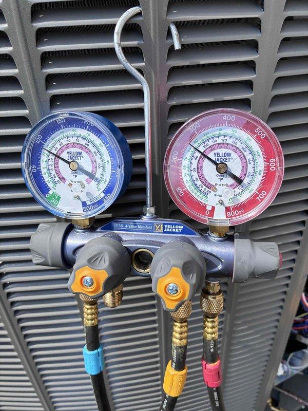 Completed warranty inspection on recently installed Lennox outdoor condensing unit. Unit was verified to be properly mounted on vibration-dampening pad with adequate clearance from structure. Connected Yellow Jacket Titan 4-valve manifold gauge set to service ports and confirmed refrigerant pressures are within manufacturer specifications for optimal system performance.