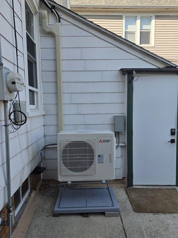 # HVAC Install - Mini Split

Completed installation of Mitsubishi Electric ductless mini-split system for residential heating and cooling. Mounted indoor wall unit above interior doorway in main living area with proper clearance and positioning for optimal air distribution. Installed outdoor condenser unit on wooden platform against exterior wall with secure mounting and level placement. Ran refrigerant lines and electrical connections through exterior wall penetration with appropriate sealing and weather protection. System tested for proper operation, refrigerant charge verified, and all components confirmed functional.