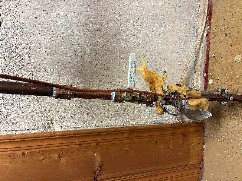 # Plumbing Service Completed

Responded to service call for copper pipe system inspection and maintenance. Upon arrival, evaluated horizontal copper supply line installation showing signs of oxidation and corrosion with characteristic greenish patina formation on exterior surfaces. Examined brass circulation pump assembly mounted at pipe terminus with integrated valve components and verified operational status of unit.

Inspected pipe mounting brackets and wall anchoring system to ensure secure attachment to structural supports. Noted presence of expanding foam insulation material around pipe joints and connection points, applied to prevent heat loss and reduce condensation. Verified integrity of all brass fittings and compression joints along horizontal run.

Assessed condition of copper piping showing age-related discoloration and mineral deposit accumulation. Confirmed proper installation technique with appropriate support spacing and clearance from wall surface. Documented existing