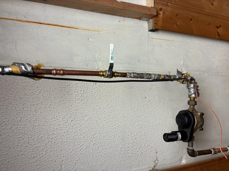 # Plumbing Service Completed

Responded to service call for copper pipe system inspection and maintenance. Upon arrival, evaluated horizontal copper supply line installation showing signs of oxidation and corrosion with characteristic greenish patina formation on exterior surfaces. Examined brass circulation pump assembly mounted at pipe terminus with integrated valve components and verified operational status of unit.

Inspected pipe mounting brackets and wall anchoring system to ensure secure attachment to structural supports. Noted presence of expanding foam insulation material around pipe joints and connection points, applied to prevent heat loss and reduce condensation. Verified integrity of all brass fittings and compression joints along horizontal run.

Assessed condition of copper piping showing age-related discoloration and mineral deposit accumulation. Confirmed proper installation technique with appropriate support spacing and clearance from wall surface. Documented existing