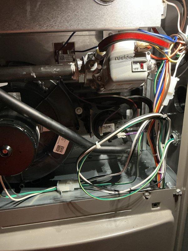 # Warranty Service Completed

Responded to warranty service call for HVAC furnace unit. Upon arrival, removed access panel to perform comprehensive system inspection. Examined all internal components including blower motor assembly, inducer motor, gas valve connections, and electrical wiring harnesses. Inspected black condensate drainage pipes for proper flow and verified no blockages present. Checked all wire connections including green ground wires and multi-colored control wiring for secure terminations. Verified proper operation of white control board with associated switching mechanisms and confirmed all safety circuits functioning correctly. Inspected metallic cylindrical motor assemblies and associated mounting hardware for secure installation. All components found operating within manufacturer specifications. Unit tested and returned to normal operation.