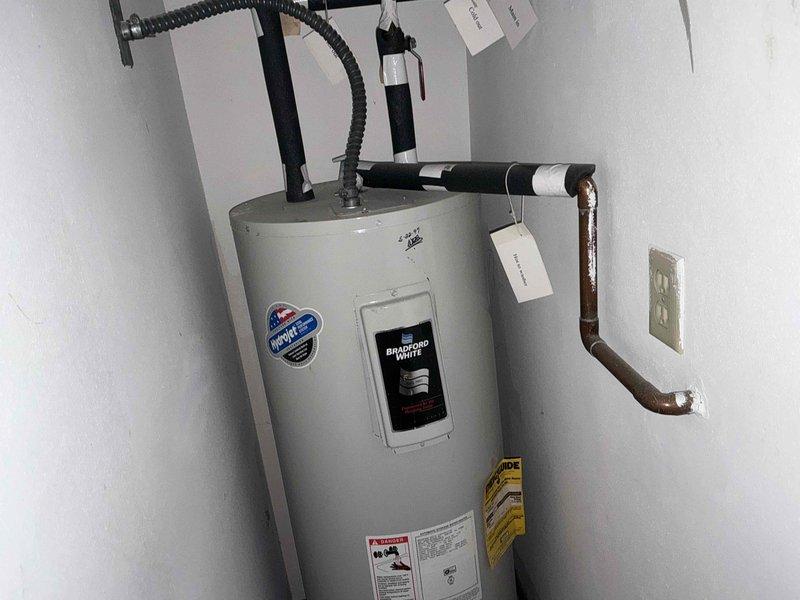 # Water Heater Inspection and Assessment

Conducted comprehensive inspection of Bradford White residential water heater installation. Evaluated all plumbing connections, including copper supply lines showing age-related oxidation and patina development. Assessed black pipe fittings and flexible gas line connections at top of unit for proper installation and code compliance. Verified earthquake strapping and wall-mounted safety restraints are properly secured to ensure unit stability. Examined venting system configuration and flexible conduit routing. Documented current condition of all components with photographic evidence, including warranty information and manufacturer specifications. Tagged multiple connection points and system components for identification purposes. Confirmed electrical outlet proximity meets safety clearance requirements and unit maintains adequate clearance within utility closet space.