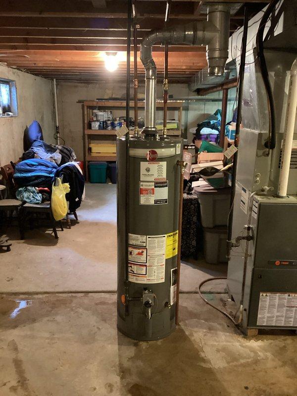 Completed installation of new residential water heater in basement utility area. Unit was properly positioned, connected to existing plumbing infrastructure with metal piping, and integrated with overhead water distribution system. All manufacturer specifications were followed, safety labels verified, and venting properly configured with aluminum ductwork extending to building exhaust system. Installation included coordination with existing HVAC furnace system to ensure proper clearances and safe operation of both appliances in shared mechanical space.