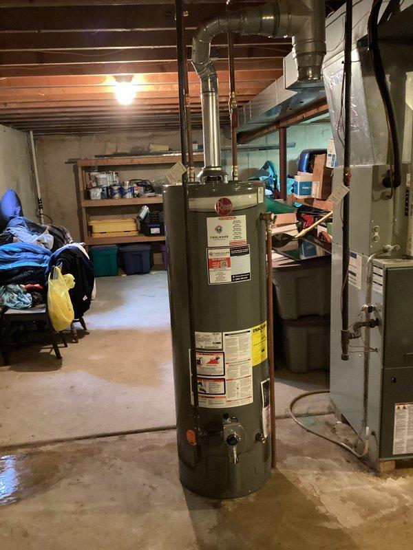 Completed installation of new residential water heater in basement utility area. Unit was properly positioned, connected to existing plumbing infrastructure with metal piping, and integrated with overhead water distribution system. All manufacturer specifications were followed, safety labels verified, and venting properly configured with aluminum ductwork extending to building exhaust system. Installation included coordination with existing HVAC furnace system to ensure proper clearances and safe operation of both appliances in shared mechanical space.