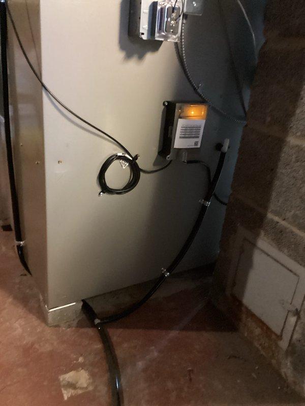 # HVAC Install - Complete System

## Summary
Completed full HVAC system installation including outdoor Carrier condenser unit with electrical service components and indoor mechanical equipment with associated connections and controls.

## Work Performed

**Outdoor Equipment Installation:**
Installed Carrier brand air conditioning condenser unit on prepared black concrete pad against exterior brick wall. Positioned unit to ensure proper clearance and accessibility for future maintenance. Mounted electrical disconnect box and meter socket on brick wall with white electrical conduit running vertically to service the outdoor unit. Secured all electrical connections per manufacturer specifications and local electrical codes. Verified proper grounding and bonding of all electrical components.

**Indoor Equipment Installation:**
Installed cylindrical mechanical equipment in basement utility area with proper clearance from walls and surrounding structures. Connected multiple refrigerant lines 
