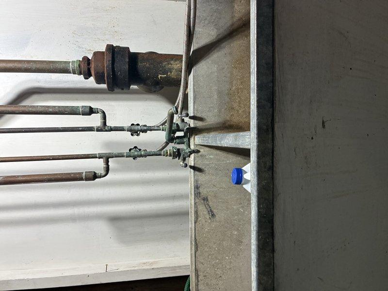 Responded to emergency call for burst copper pipe in basement mechanical room. Upon arrival, found severely corroded copper water line with active leak at fitting connection, causing water damage and staining on surrounding concrete walls. Shut off main water supply to prevent further flooding and damage to the area.

Removed deteriorated section of copper piping showing extensive oxidation and corrosion at joints and fittings. The aged copper system had failed at a compromised connection point where rust and mineral buildup had weakened the pipe integrity. Cut out damaged section and prepared pipe ends for replacement.

Installed new copper pipe segment with proper fittings and soldered connections to restore water line integrity. Tested all joints for leaks and verified proper water pressure throughout the system. Confirmed no additional weak points in adjacent piping. Restored water service to the property and verified all fixtures operating correctly.