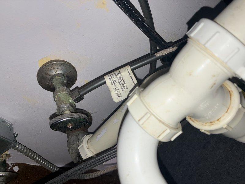 # Plumbing Inspection Report

Completed comprehensive plumbing inspection of drainage system and utility connections in crawl space area. Inspection revealed significant corrosion and green patina buildup on brass valve fitting connected to PVC P-trap assembly, indicating potential age-related deterioration requiring monitoring. Documented ceiling discoloration, rust staining around pipe connections, and overall condition of white PVC drainage piping, flexible corrugated metal hose, and black electrical cable routing through the space. Photographed exposed floor joists, structural framing, vertical black utility pipes with galvanized metal fittings, and textured wall surfaces to provide visual record of current system configuration and condition for future maintenance reference.