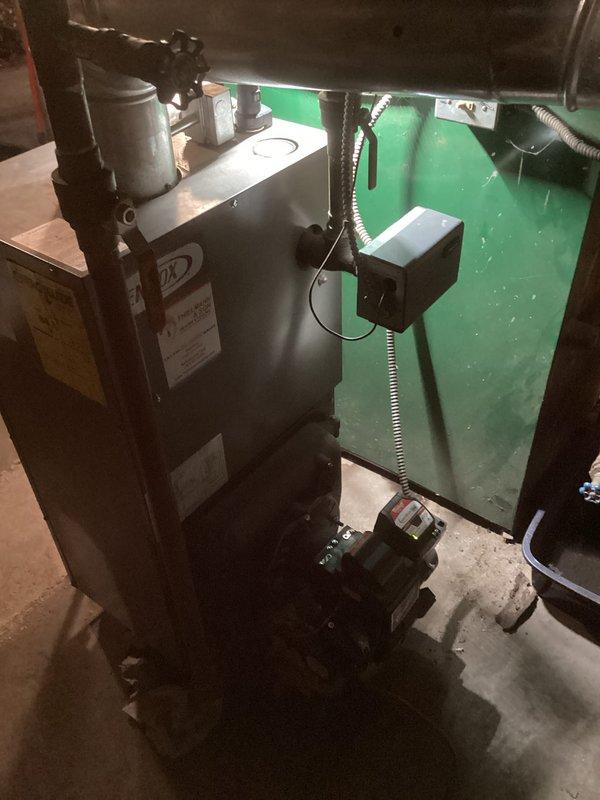 Completed comprehensive boiler system inspection and maintenance in residential basement utility area. Serviced oil-fired boiler unit including burner assembly, fuel pump, and associated copper piping with pressure relief valve system. Verified proper operation of all components, checked connections throughout the heating system, and ensured ductwork integration was functioning correctly with no visible leaks or safety concerns detected.