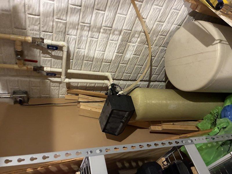 Completed installation and configuration of water treatment system components in attic utility space, including connection of PVC supply lines with shutoff valves to main treatment tank. Verified proper plumbing integration with existing copper piping, tested system operation, and confirmed all connections were secure and leak-free.