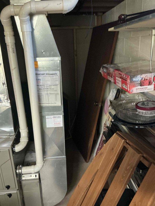 Completed comprehensive HVAC system evaluation for equipment replacement in residential basement utility area. Assessed existing furnace/air handler unit and water heater configuration, documenting current installation conditions including PVC condensate drainage, venting systems, and spatial requirements for new equipment installation. Photographed existing equipment specifications, clearances, and utility connections to develop accurate replacement proposal for updated high-efficiency heating system.