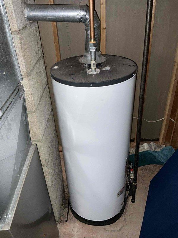 Completed comprehensive HVAC system evaluation for equipment replacement in residential basement utility area. Assessed existing furnace/air handler unit and water heater configuration, documenting current installation conditions including PVC condensate drainage, venting systems, and spatial requirements for new equipment installation. Photographed existing equipment specifications, clearances, and utility connections to develop accurate replacement proposal for updated high-efficiency heating system.