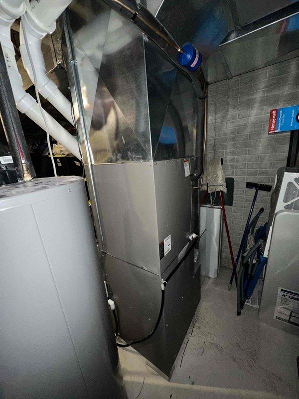 Completed full HVAC system replacement including installation of new high-efficiency furnace in basement mechanical room and matching outdoor condensing unit. Furnace was positioned on existing concrete pad with proper clearances, connected to white PVC venting system for intake and exhaust, and integrated with existing ductwork distribution system. Outdoor condensing unit was set on level concrete pad with appropriate drainage, electrical disconnect box mounted to exterior wall with PVC conduit for line set protection, and all refrigerant lines properly insulated and secured. System was pressure tested, evacuated, charged to manufacturer specifications, and cycled through multiple heating and cooling operations to verify proper function of all components including blower motor, compressor, and safety controls.