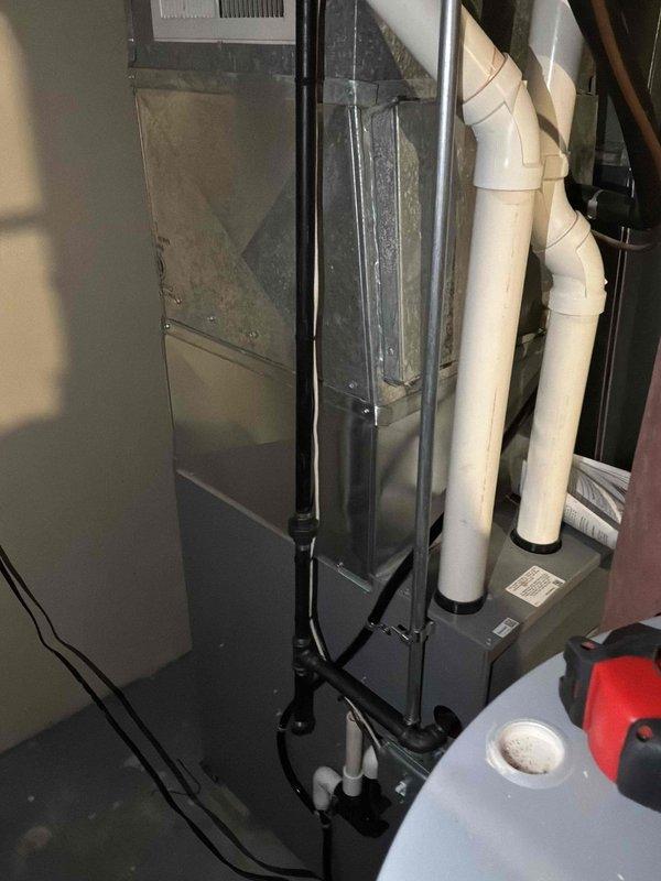 Completed HVAC system replacement in residential basement utility area. Installed new air handler unit with associated ductwork, condensate drainage system utilizing white PVC piping with proper fittings and elbows, and electrical connections including control box mounting. Configured flexible aluminum ductwork to floor register for proper air distribution throughout the residence.