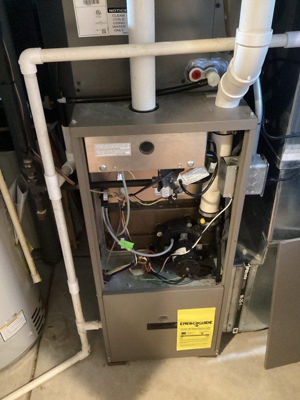 # HVAC Furnace Inspection and Maintenance

Performed comprehensive inspection and maintenance service on residential gas furnace system. Removed front access panel to evaluate internal components including blower motor assembly, gas burners, ignition system, and electrical connections. Inspected black circular blower motor mounted within cabinet, verifying secure mounting bolts and examining cooling vents for proper airflow. Checked all electrical wiring connections including red, white, and green conductor terminations to motor and control board.

Examined PVC condensate drain lines and venting system for proper installation and drainage. Verified yellow capacitor functionality and connections. Inspected gas burner assembly, ignition components, and flame sensing mechanisms for proper operation. Evaluated all safety controls and limit switches. Confirmed EnergyGuide label present and system specifications. All components found operating within normal parameters. System tested and retu