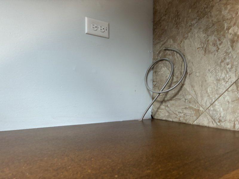 Completed water service installation connecting supply lines to water heater. Installed shut-off valves on copper supply lines with flexible braided stainless steel connectors, utilizing brass fittings with rubber washers to ensure proper sealing and prevent leaks at connection points.