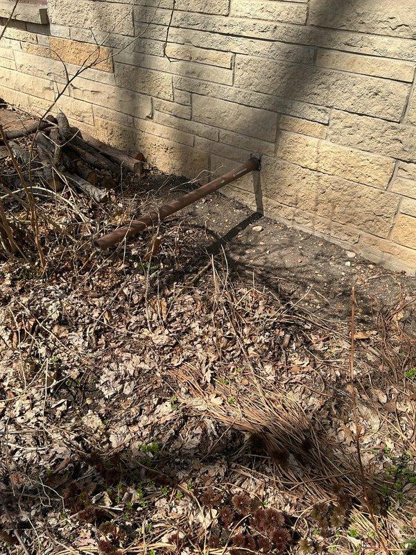 Conducted plumbing estimate for pump system evaluation in basement utility area. Inspected aged vertical discharge pipe showing significant oxidation and weathered patina, assessed electrical connections and wiring runs associated with existing pump installation. Examined exterior foundation perimeter where debris accumulation near building corner may impact drainage systems and potential pump discharge lines, noted need for clearance to ensure proper water evacuation from pump operations.