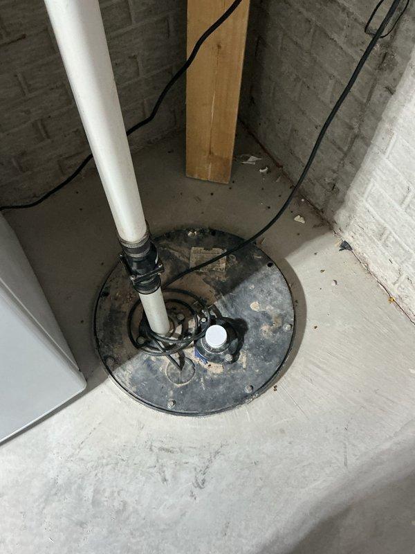Completed inspection and maintenance of residential sump pump system located in basement utility area. Verified proper operation of sump pump basin, checked PVC discharge piping for secure mounting and adequate flow capacity, and inspected electrical connections for safety and functionality. All components found to be in working order with pump cycling appropriately and discharge line properly secured to prevent water backup issues.