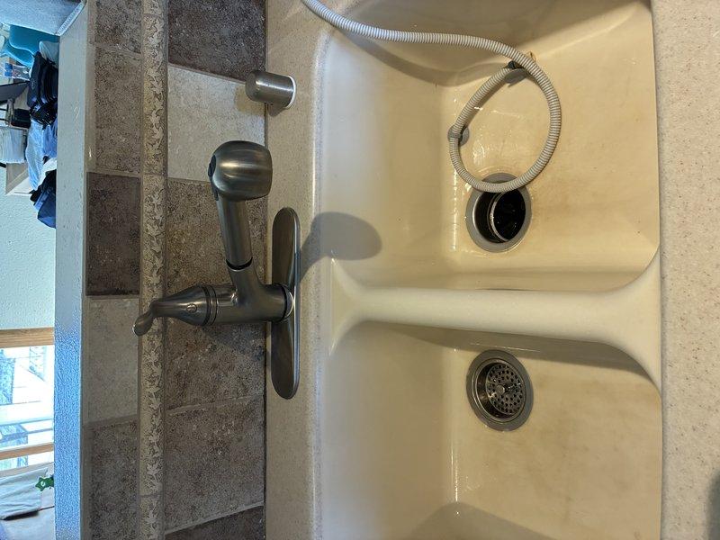# Plumbing Service - Faucet

Installed new kitchen sink faucet assembly with pull-out spray head and brushed metal finish in double-basin sink configuration. Connected dishwasher drain hose to proper drainage point and verified all plumbing connections for leaks and proper water flow.