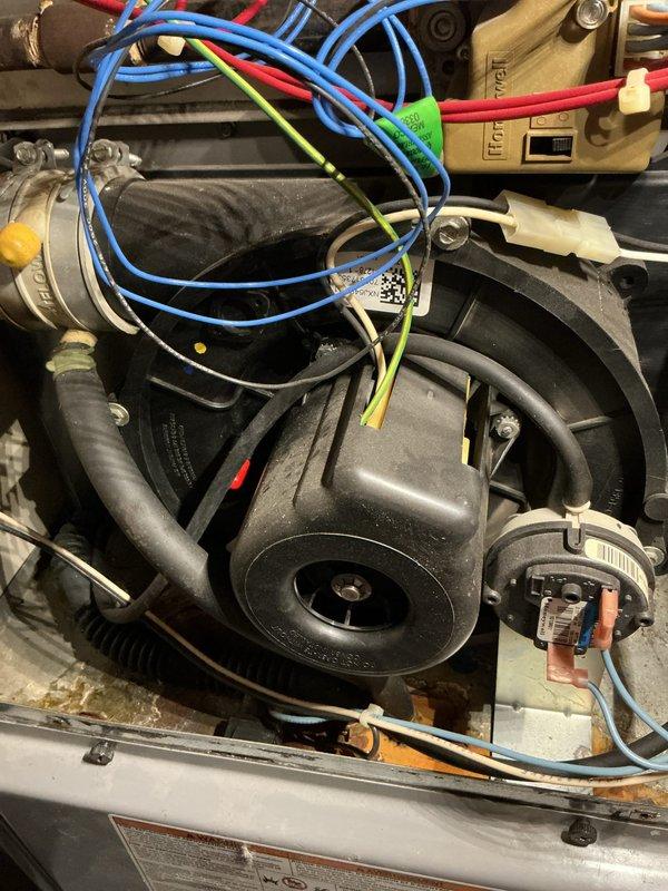 Performed furnace inspection and documented equipment condition. Found evidence of significant moisture infiltration and staining on exterior cabinet panels, indicating potential condensate drainage issues or heat exchanger concerns. Inspected internal blower assembly and motor components, verified proper wiring connections and electrical connections to motor and control relays. All internal components appeared functional with normal wear patterns on blower housing and mounting platform showing age-related surface oxidation.
