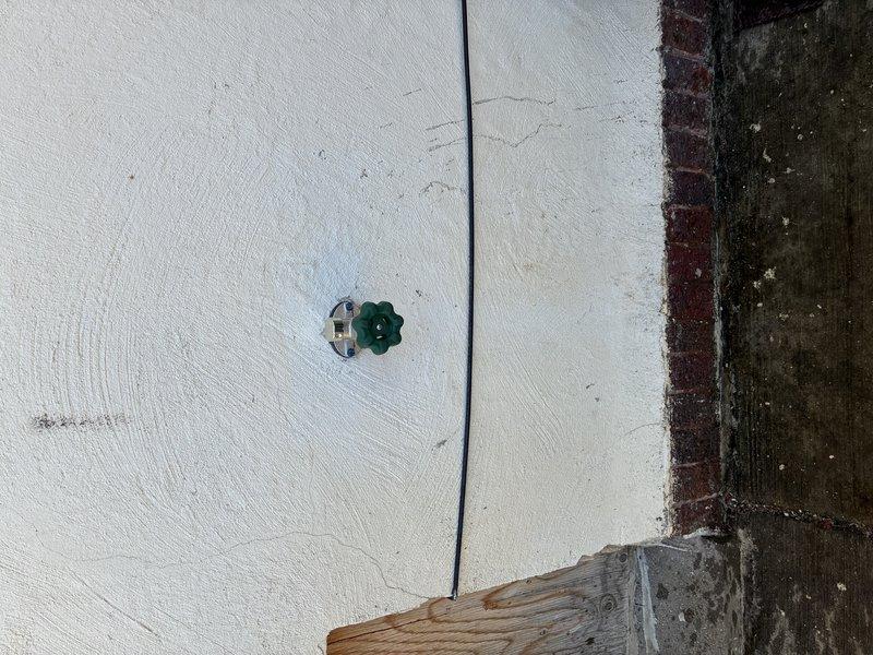 Conducted comprehensive plumbing fixture assessment in utility area with aging infrastructure. Inspected copper and PVC water supply lines at wall junction, evaluated shut-off valve functionality and condition, and documented deteriorated wooden framing with moisture damage and biological growth around plumbing penetrations. Photographed existing conditions including painted surface deterioration, pipe routing configuration, and valve accessibility for fixture replacement estimate preparation.