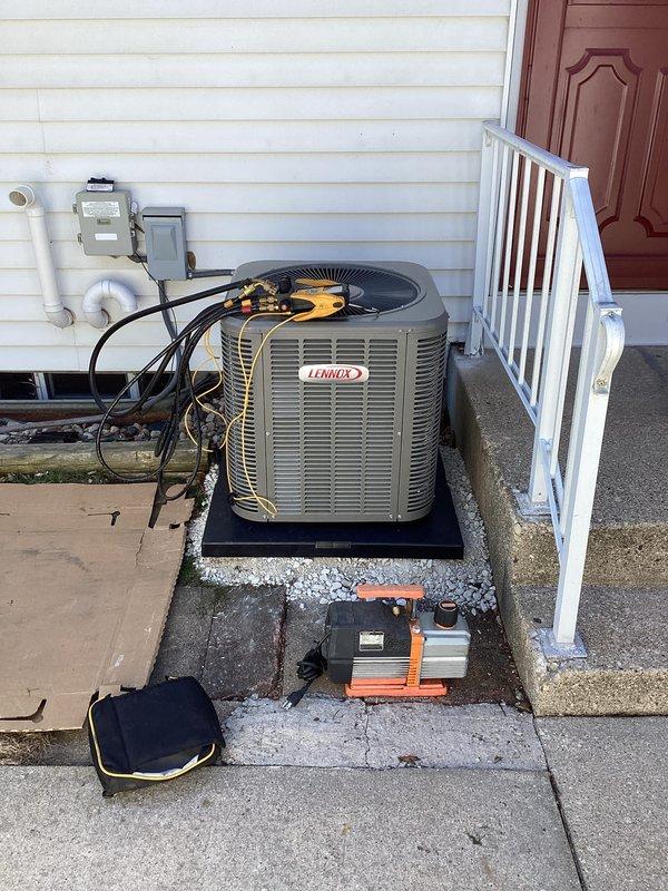 Completed full HVAC system installation featuring a Lennox cylindrical condenser unit mounted on vibration-dampening pad with proper gravel base for drainage and stability. Installed electrical disconnect box with conduit run to unit, routed and insulated refrigerant lines to indoor air handler, evacuated system using vacuum pump to remove moisture and contaminants, and charged system to manufacturer specifications. Performed diagnostic verification using manifold gauges and digital meter, confirming proper refrigerant pressures, temperatures, and system operation across all parameters.