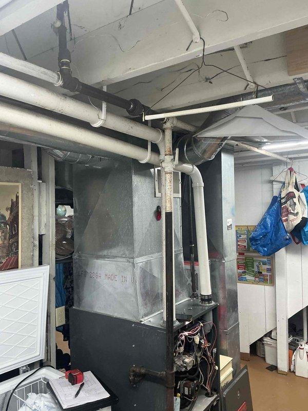 Conducted comprehensive assessment of existing HVAC system in residential basement mechanical room. Evaluated aging furnace/air handler unit showing significant wear, surface deterioration, and outdated components with exposed internal wiring and mechanical systems. Documented current equipment configuration including ductwork layout, ventilation piping, and electrical connections to provide accurate replacement specifications and system upgrade recommendations.