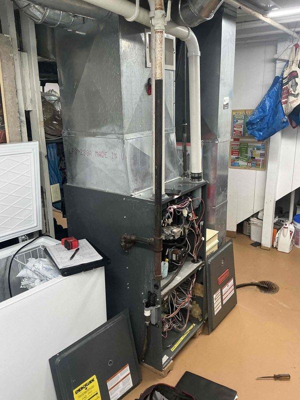 Conducted comprehensive assessment of existing HVAC system in residential basement mechanical room. Evaluated aging furnace/air handler unit showing significant wear, surface deterioration, and outdated components with exposed internal wiring and mechanical systems. Documented current equipment configuration including ductwork layout, ventilation piping, and electrical connections to provide accurate replacement specifications and system upgrade recommendations.