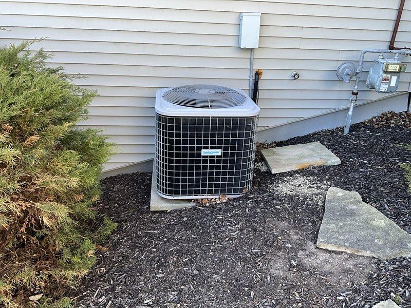 Completed HVAC estimate for replacement of existing outdoor air conditioning system. Assessed current cylindrical condenser unit with protective metal grille installed on concrete pad with proper electrical disconnect and conduit configuration. Evaluated equipment specifications including model E110500357, verified UL and AHRI certifications, and documented existing installation conditions including landscaping clearances, stepping stone access path, and proper unit positioning on level concrete pad for adequate drainage and stability.