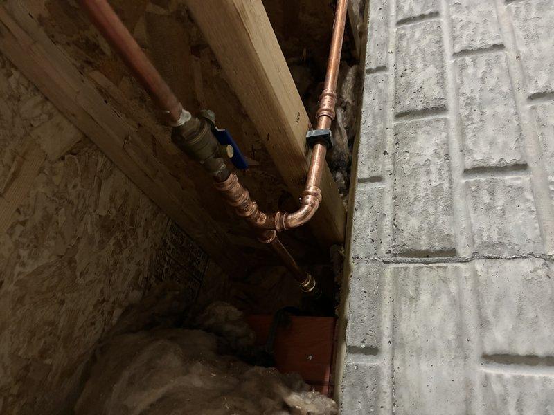 # Outdoor Spigot Pipe Replacement

Replaced severely corroded copper pipe serving outdoor spigot system. The existing pipe had failed due to extensive corrosion and perforation, causing water leakage. Removed damaged section with corroded brass fittings and installed new copper piping with proper connections to existing basement plumbing infrastructure. Installed shut-off valve for future maintenance access. System tested and confirmed operational with no leaks.