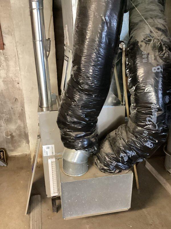 Completed furnace installation in basement utility area. New system includes properly sized supply and return ductwork with insulated flexible ducting connected to metal plenum. All vent piping installed to code specifications with appropriate PVC materials for condensate drainage and exhaust venting through exterior wall penetration.