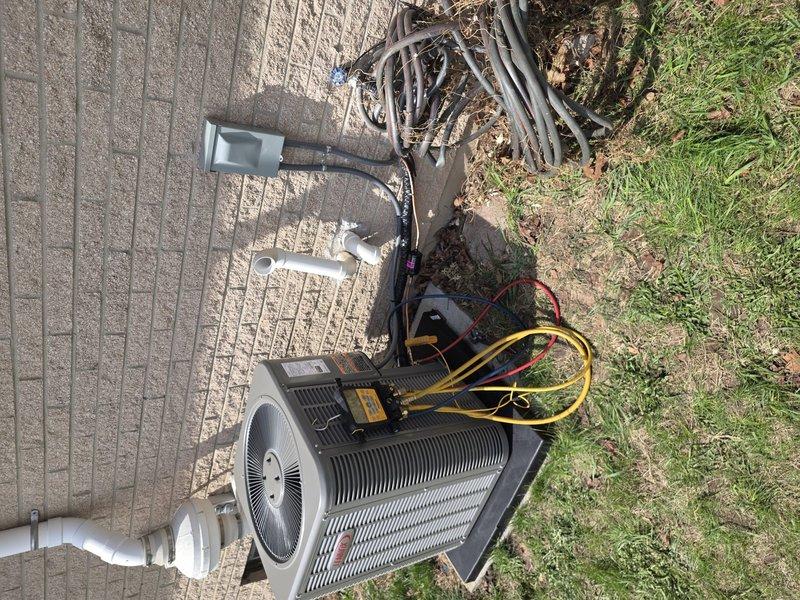 # HVAC Install - A/C & Coil

Completed installation of new air conditioning system including outdoor condensing unit and indoor evaporator coil. Installed outdoor unit on textured concrete pad with proper leveling and positioning adjacent to building structure. Connected refrigerant lines between outdoor condenser and indoor coil using appropriate line sets with proper insulation. Established PVC condensate drainage system with multiple connection points and proper pitch for efficient water removal from evaporator coil. Integrated new coil assembly into existing ductwork infrastructure within mechanical space, ensuring proper airflow alignment with return air plenum and filter access. Performed vacuum and pressure testing of refrigerant system using digital manifold gauges to verify system integrity and absence of leaks. Charged system with manufacturer-specified refrigerant to proper levels based on line length and ambient conditions. Verified electrical connections at both indoor and