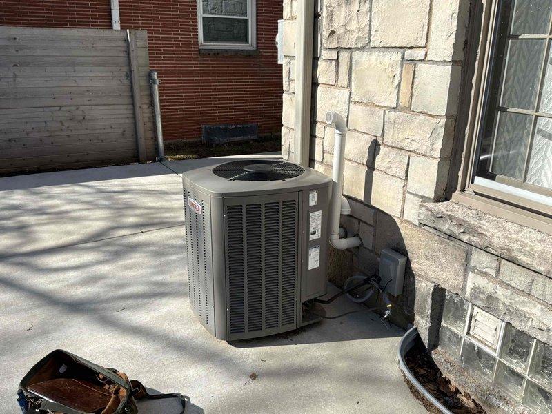 Completed full HVAC system replacement at residential property. Removed existing outdoor condensing unit and installed new air conditioning system on concrete pad adjacent to exterior wall. Routed refrigerant lines along building exterior using gray insulated copper piping with proper foam insulation, secured electrical disconnect box, and connected all necessary electrical wiring and communication cables. System installation included proper line set configuration, refrigerant charging, and verification of all connections to ensure optimal performance and compliance with manufacturer specifications.