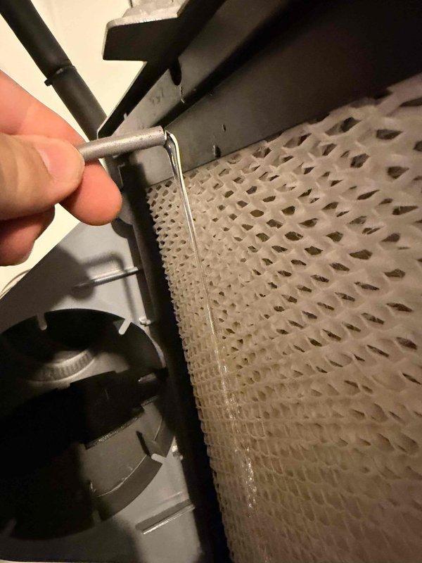 Performed indoor air quality inspection and maintenance on residential HVAC air handler system. Inspected evaporator coil assembly and cylindrical filter element for cleanliness and proper airflow, confirming perforated filter media was functioning correctly with adequate moisture drainage. Verified refrigerant line connections, brass valve fittings, electrical wiring connections, and all mounting hardware were secure and operating within normal parameters.