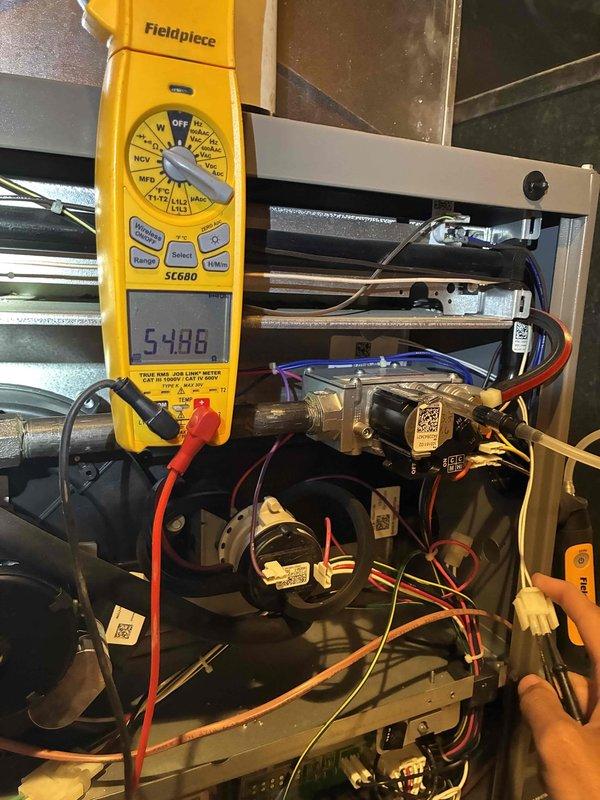 Performed diagnostic inspection and electrical testing on residential furnace system. Using digital multimeter, measured and verified proper voltage readings across gas valve assembly and motor components, confirming electrical functionality at 5486 ohms resistance. Inspected blower motor assembly, fan blade, and associated wiring connections including control wiring harnesses. All components showed normal operational wear with minor dust accumulation on blower assembly, which is typical for seasonal equipment usage.