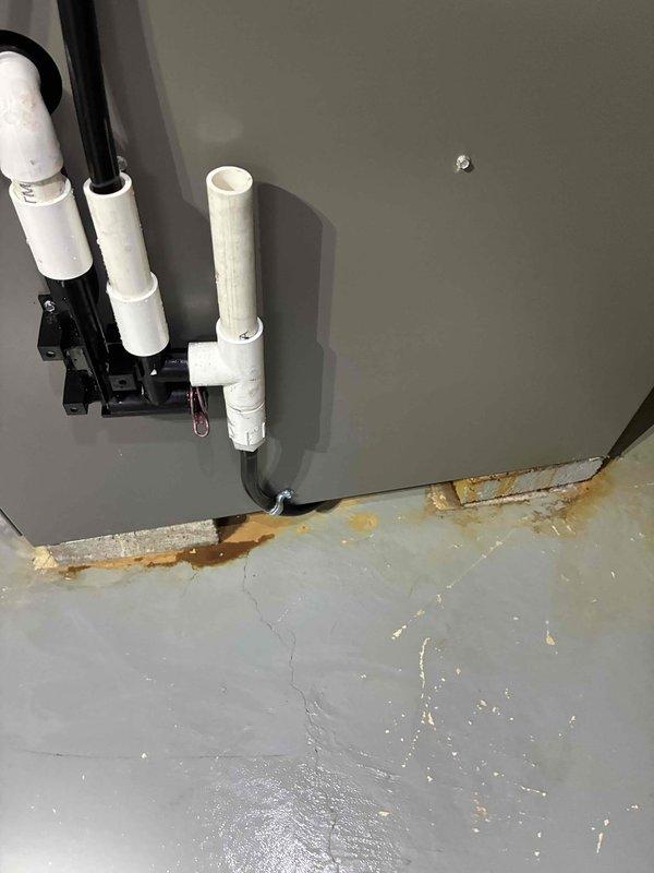 Completed installation of Lennox furnace unit in residential basement utility space. Unit was positioned on concrete floor with protective foam padding, connected to existing ductwork system including metal supply ducts and white PVC condensate drain lines. During installation, identified existing water infiltration issues at wall-to-floor junction near piping penetrations, evidenced by discoloration and moisture damage to substrate materials. All mechanical connections, venting, and drain lines were properly secured with appropriate mounting brackets and fittings to ensure code-compliant operation.