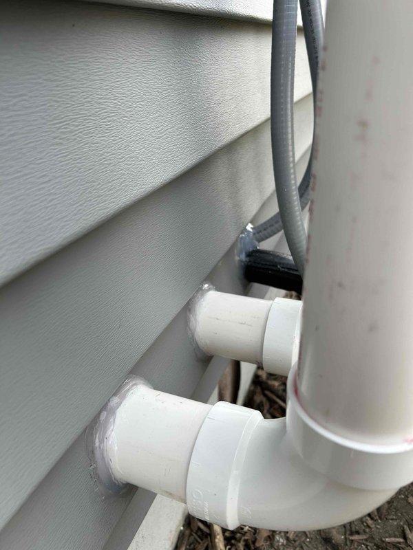 # HVAC Complete System Installation

Successfully completed a full HVAC system installation including both interior and exterior components. Installed new air handler unit in mechanical room on concrete pad with proper drainage provisions. Routed and secured copper refrigerant lines, electrical conduit, and condensate drainage lines throughout the installation. Mounted exterior condensing unit on building with appropriate line set penetrations through vinyl siding. Installed white PVC condensate drain lines with proper pitch and termination points at building exterior. Connected all electrical components including junction boxes and power supply conduit. Secured all refrigerant lines with proper insulation and bundling. Installed Amtrol expansion tank and associated plumbing connections. Completed all refrigerant line connections, pressure testing, and system evacuation. Energized system and verified proper operation of all components including heating and cooling cycles. All installat