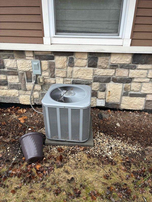Completed comprehensive estimate for full HVAC system replacement including gas furnace and outdoor condensing unit. Evaluated existing basement-installed furnace with exposed burner assembly and outdoor air conditioner positioned on concrete pad against stone foundation exterior. Assessed current system configuration including refrigerant line routing, electrical disconnect placement, PVC venting, and equipment accessibility for replacement planning.