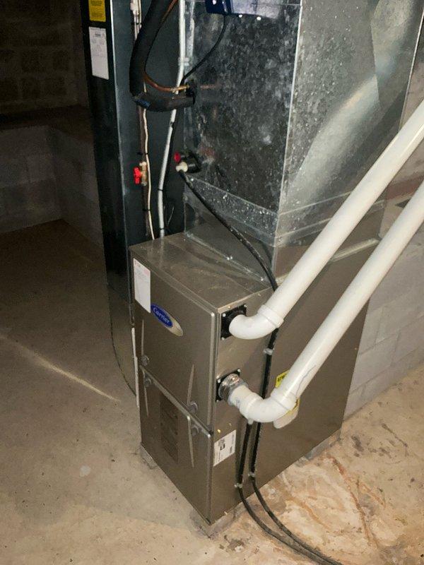 Completed HVAC system replacement in residential basement utility area. Installed new furnace unit with associated ductwork, PVC condensate drain lines, refrigerant lines, and electrical connections on existing concrete pad. All components properly connected and tested for proper operation.