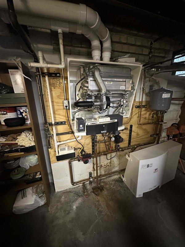 Conducted comprehensive assessment of basement mechanical room boiler system and associated HVAC components. Documented existing equipment configuration including wall-mounted heating units, copper and PVC piping networks, control boxes, expansion tank, and ventilation ductwork. Evaluated system layout, pipe connections with black valve handles, and overall mechanical infrastructure to provide accurate estimate for boiler replacement or upgrade requirements.