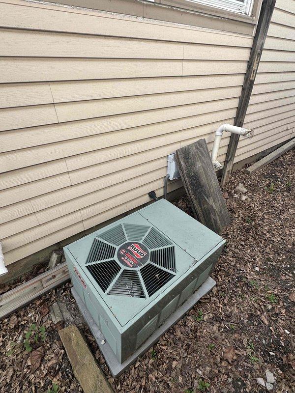 Completed comprehensive HVAC system replacement estimate for residential property with aging outdoor condensing unit and existing electrical infrastructure. Assessed current light green/turquoise condenser unit positioned on concrete pad against exterior wall, evaluated electrical panel configuration including Square D and Techni-Center breaker boxes mounted in utility area, and documented existing electrical capacity and conduit routing to determine replacement system requirements and installation specifications.