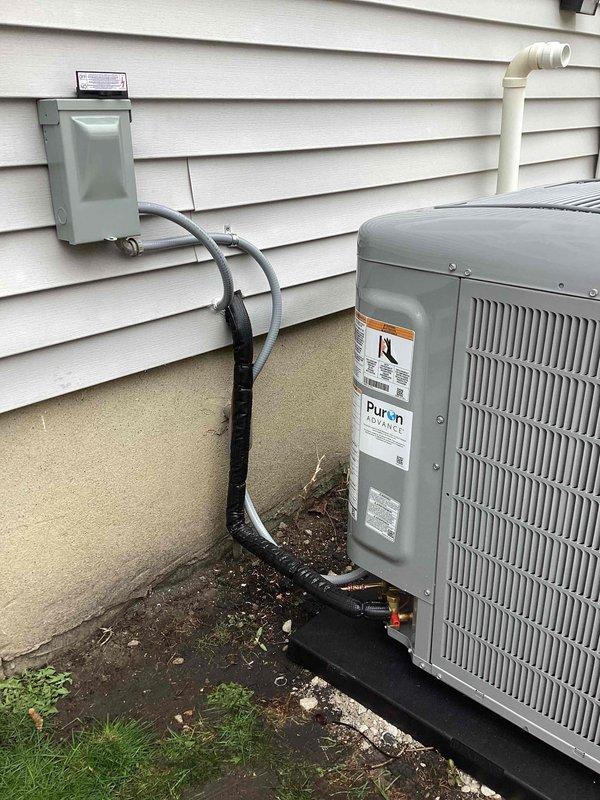 Completed installation of new Pureon air conditioning system including outdoor condenser unit and evaporator coil. Mounted condenser on composite pad adjacent to exterior wall, established refrigerant line connections with proper insulation, installed electrical disconnect box, and routed PVC condensate drain line vertically along siding. System tested and verified operational with all components functioning within manufacturer specifications.