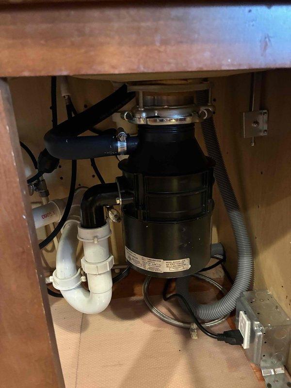 # Plumbing Install - Outdoor Spigot/Shower

Installed new garbage disposal unit beneath kitchen sink, including complete mounting assembly with stainless steel flange connection to sink drain. Connected disposal to existing drainage system using white PVC P-trap configuration and secured all pipe joints. Ran electrical connection from disposal unit to cabinet-mounted outlet and verified proper power supply. Installed black corrugated discharge hose for drainage routing and ensured all connections were watertight and secure.